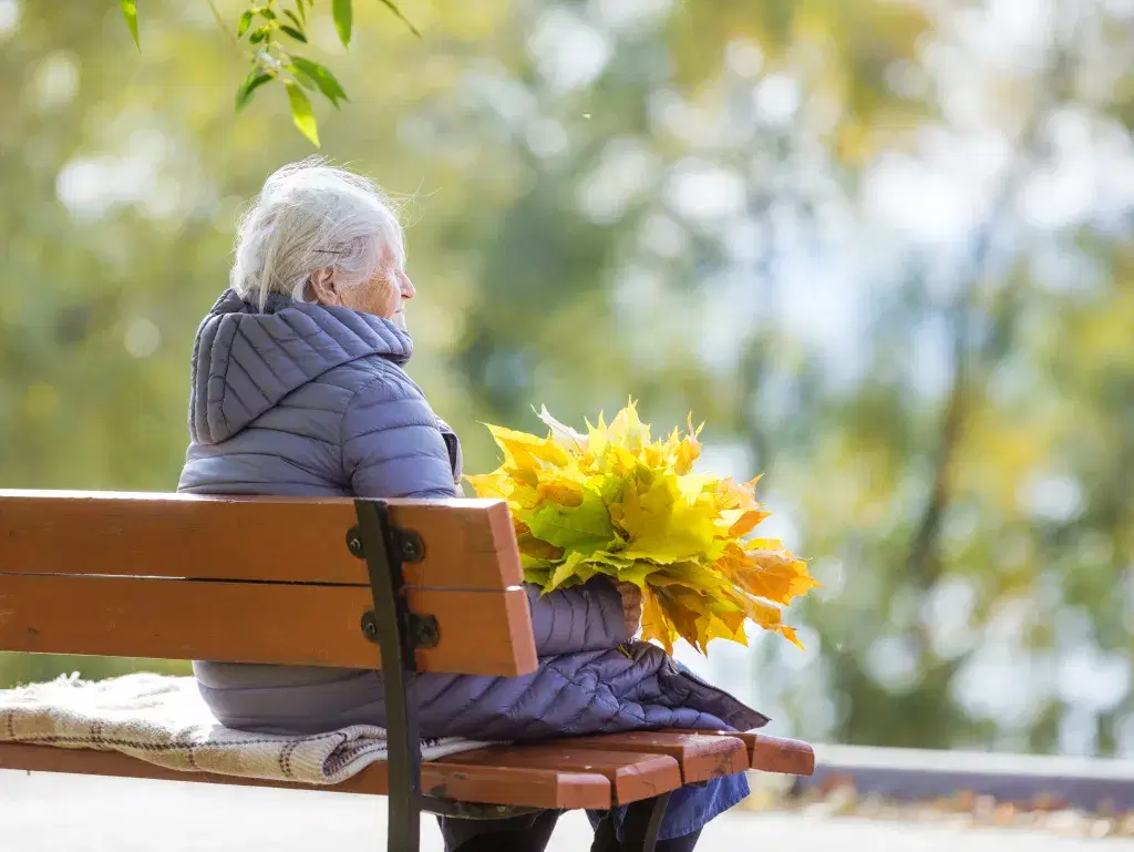 senior-woman-sitting-on-bench-in-park-and-holding-2026-01-07-01-35-59-utc